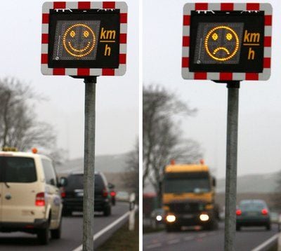 Auf einem elektronischen Geschwindigkeitswarngerät, das an einer Bundesstraße steht, wird mit einem lachenden (l.) oder einen traurigen Smiley über die Einhaltung der vorgegebenen Geschwindigkeit informiert. (FOTO: DPA)