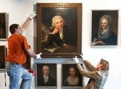Im Freundschaftstempel des Gleimhauses in Halberstadt justieren Museumsdirektorin Ute Pott (r.) und der Haustechniker Volker Niens ein historisches Bild von Johann Wilhelm Ludwig Gleim. (Archivfoto: dpa)