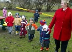 Erzieherin Rosemarie Pfeifer mit Kindern auf dem Spielplatz der Kinderkrippe «Wiesenschlümpfe» in Magdeburg (Foto: dpa)