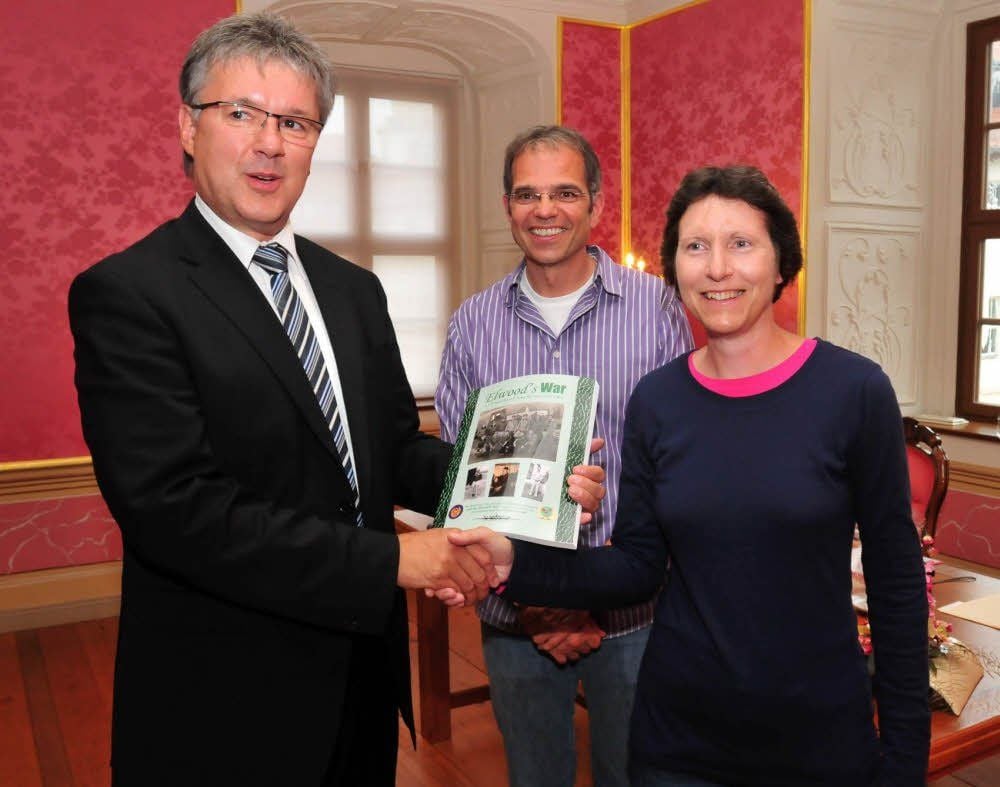 Oberbürgermeister Robby Risch (links) erhält von Loraine Koski und deren Ehemann Jim das Exemplar.