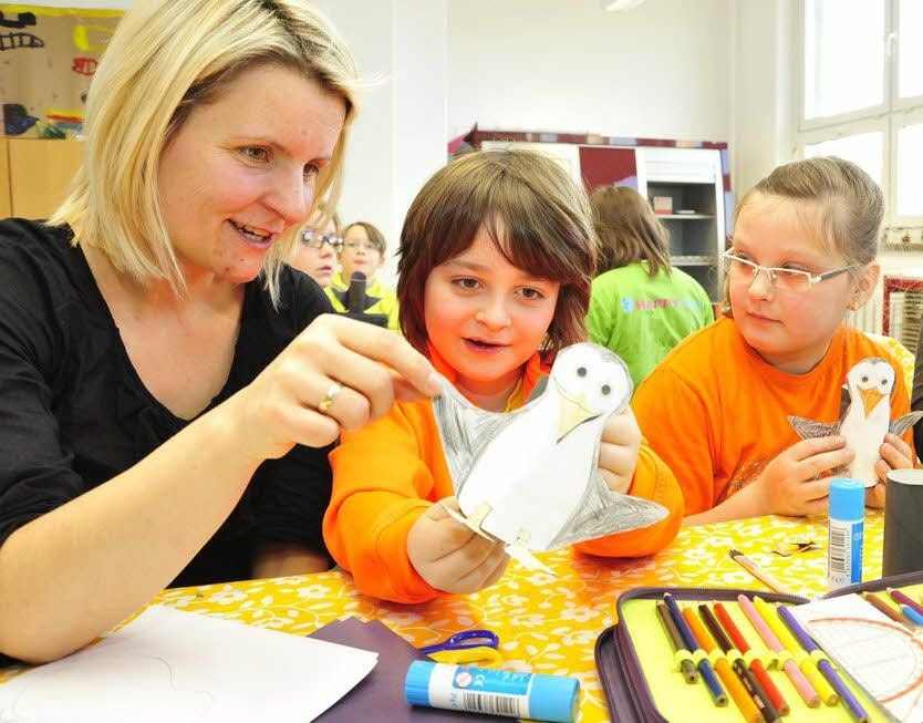 Lehrerin Ariana Bittner (von links) bastelt mit Maximilian Abendroth (6 Jahre alt) und Franziska Marie Fiebig (8) lustige Pinguine. Die Kommunikation läuft ausschließlich in Englisch.