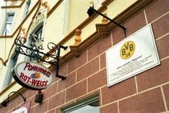Einst die Kneipe «Zum Wildschütz», heute die Imbissbude «Pommes Rot-Weiß» - eine Plakette an der Hauswand erinnert daran, dass in diesem Haus an der Oesterholzstraße im Dezember 1909 der Verein Borussia Dortmund gegründet worden ist. (Foto: dpa)