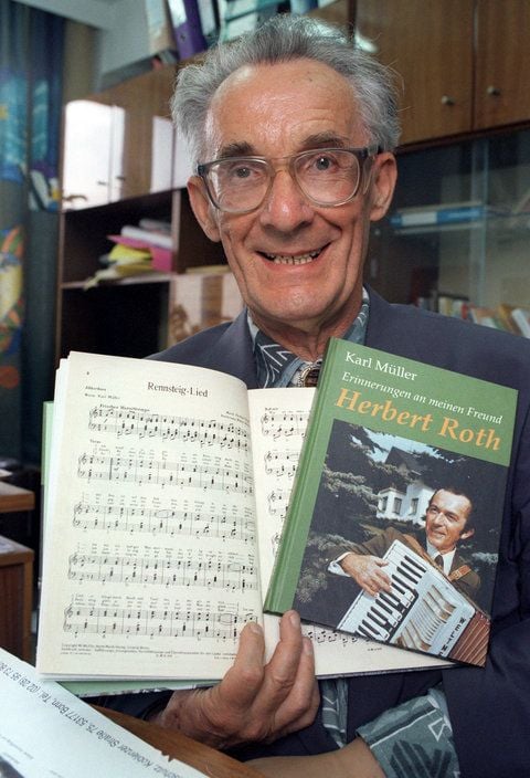 Der Texter des Rennsteigliedes, Karl Müller, hält ein Erinnerungsbuch von Herbert Roth in Händen. Karl Müller, ist im Alter von 86 Jahren in Suhl gestorben. (FOTO: DPA)