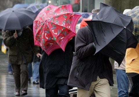 Fußgänger kämpfen mit ihren Regenschirmen. (FOTO: DPA)