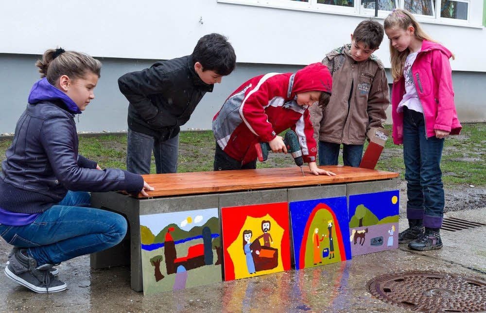 Emely, Renas, Pascal, Marvin und Sarah (von links) montieren die Sitzfläche an die Bank.