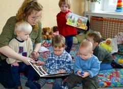 Die Erzieherin Kathrin Drümecker erklärt am in der Kinderkrippe Wiesenschlümpfe in Magdeburg ihren Kindern die Bilder eines Buches. (Archivfoto: dpa)