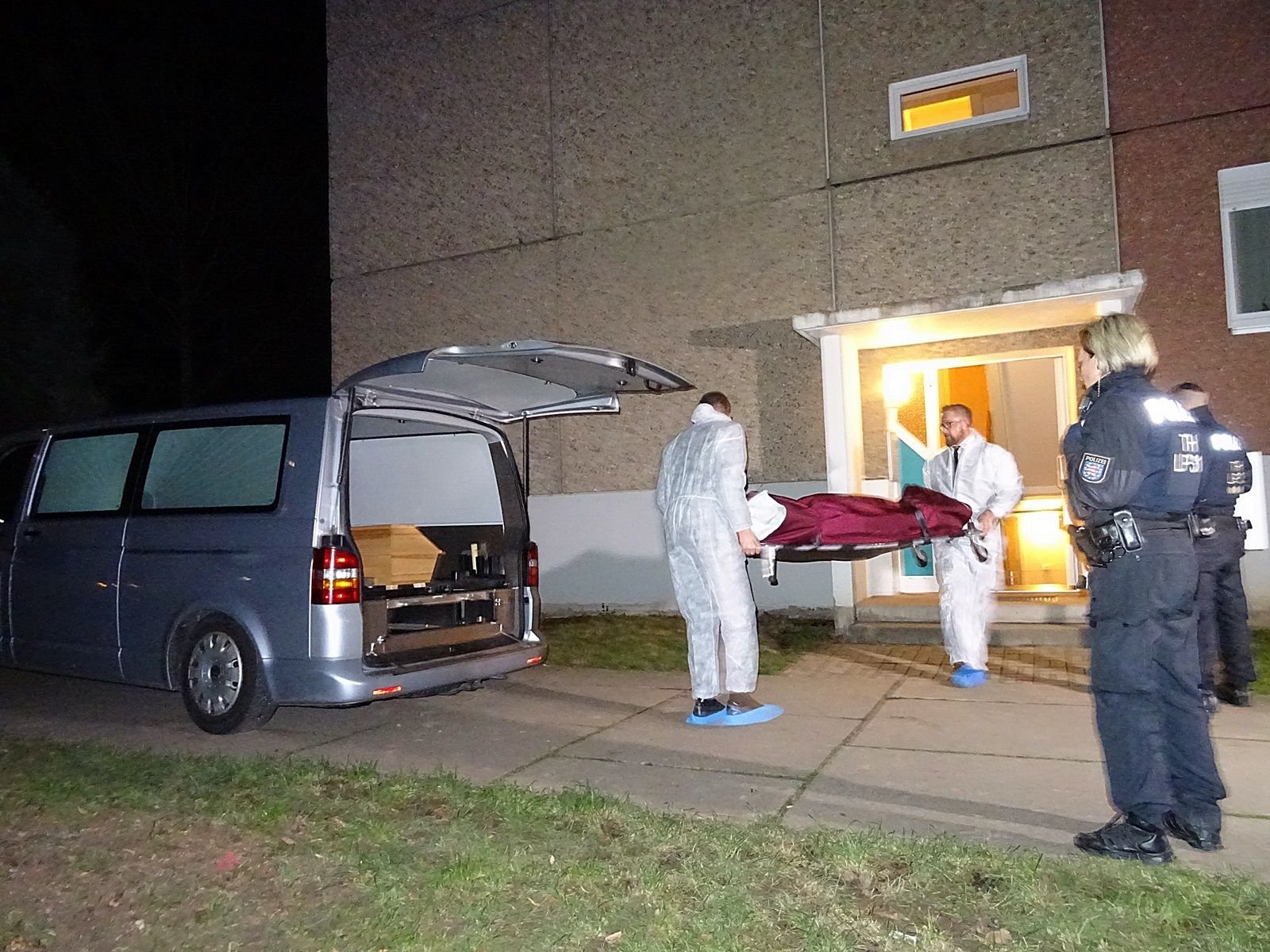 Ein Toter wird aus einem Wohnhaus im Jenaer Stadtteil Winzerla zu einem Auto getragen, in dem bereits ein Sarg steht.