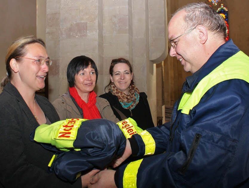 Der Leiter der Notfallseelsorge, Vinzenz Matscha, überreicht Madlen Calame, Corinna Krüger und Janine Hoffmann (v. l) ihre Einsatzkleidung.