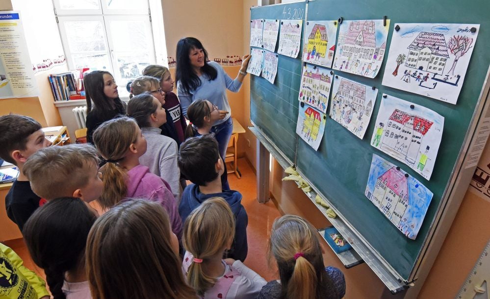 Kunstlehrerin Steffi Schleichardt schaut sich mit den Dritt- und Viertklässlern der Hoymer Grundschule die Bilder an, die auf die Umfrage-Postkarte kommen sollen.