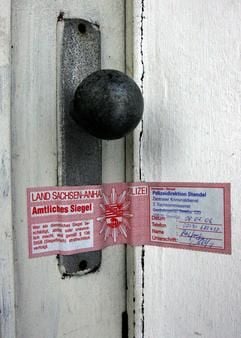 Ein Siegel mit dem Stempel der Polizeidirektion Stendal klebt über einer Tür am Wohnhaus einer Familie in Schlagenthin (Jerichower Land).