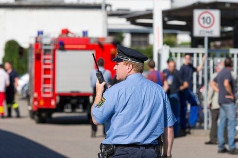 Ein Polizist hält bei einem Brand in der Druckguss Heidenau GmbH in Dohna am Haupteingang des Automobilzulieferers ein Funkgerät. (FOTO: DAPD)