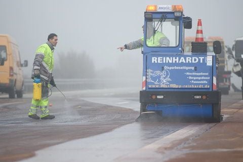 Helfer reinigen am 23.11.11 nach einer Massenkarambolage auf der Autobahn 9 (A9) zwischen Klein Marzehns und Niemegk im Landkreis Potsdam Mittelmark den Asphalt mit einer Spezialmaschine vom Öl. (FOTO: DAPD)