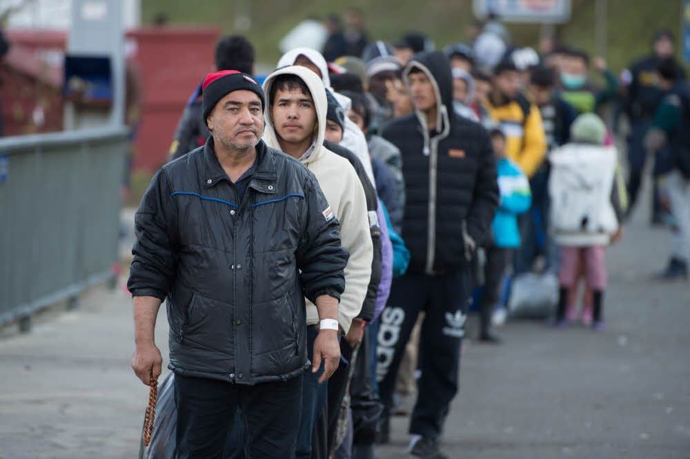 Angekommen in Deutschland – Migranten nach dem Grenzübertritt in der Nähe des bayerischen Dorfes WegscheidFlüchtlinge aus Afghanistan warten bei Wegscheid auf den Grenzübertritt nach Deutschland.Rotkreuz-Mitarbeiter verteilen an der Grenze bei Passau Obst an die Flüchtlinge.