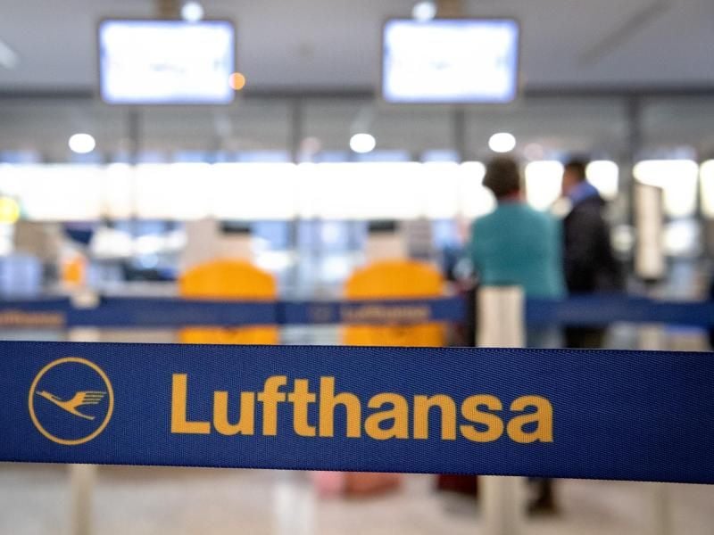 Passagiere laufen auf den Lufthansa-Schalter am Flughafen zu. Foto: Sina Schuldt/dpa/Archivbild