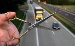 Eine Hand ist mit geöffneter Schere über einer Autobahn nahe dem brandenburgischen Briesen zu sehen. (Foto: dpa)
