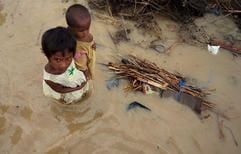 Ein kleines Mädchen trägt ein Kleinkind durch den überschwemmten Ort Gurgaon, rund 30 Kilometer entfernt von Neu Delhi. (Foto: dpa)