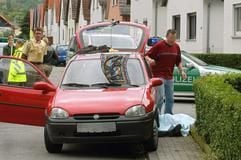 Polizisten stehen neben der abgdeckten Leiche eines mutmaßlichen Straftäters und dem Auto am Samstag (27.05.2006) im badischen Hemsbach. Ein Ehepaar aus dem pfälzischen Frankenthal ist am Samstagmorgen in seiner Wohnung erschossen worden. (Foto: dpa)