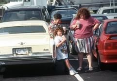 Eine übergewichtige Frau steht mit ihrer Familie auf dem Parkplatz eines US-Einkaufszentrums und stärkt sich mit einem Getränk. (Foto: dpa)
