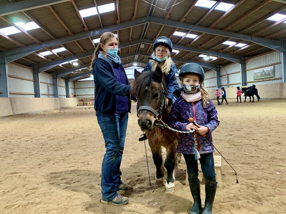 Emely, die auf dem Rücken des Ponys sitzt, vertraut ihrer Reitfreundin Friedericke, die das Kleinpferd führt. Alexandra Scheffler arbeitet mit der Hippolini-Methode.