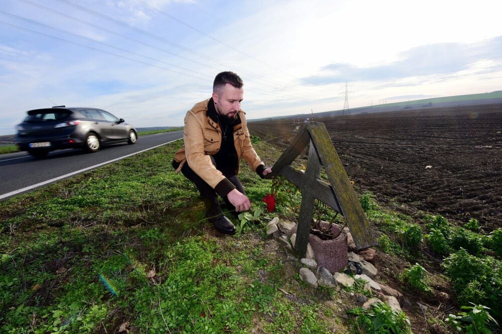 Philipp Bursian legt eine Rose an dem Straßenkreuz an der B80 nieder.