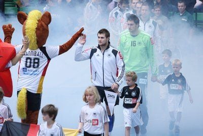 Der Deutsche Handballer Michael Kraus (M) klatscht beim Supercup in halle/Westfalen mit Maskottchen Hannibal (l) ab. (FOTO: DPA)