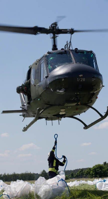 Wieder schleppen Hubschrauber Sandsäcke in Big-Bags herbei.