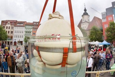 Besucher betrachten am Samstag auf dem Marktplatz in Jena größten Kartoffelkloß der Welt in einem extra dafür gefertigtem Glaskochtopf. Die Einnahmen aus dem Kloßverkauf sollen in die Sanierung der Lobdeburg fließen. (FOTO: DPA)