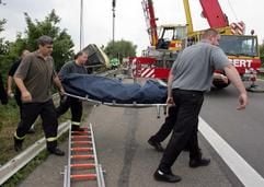 Helfer tragen eine Leiche aus dem Wrack eines verunglückten dänischen Reisebusses am Sonntag (18.07.2004) an einer Brücke an der A1 bei Euskirchen. (Foto: dpa)