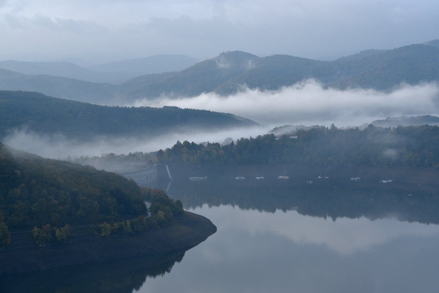 Nebelschwaden spiegeln sich nach Sonnenaufgang im Edersee bei Waldeck (Hessen).