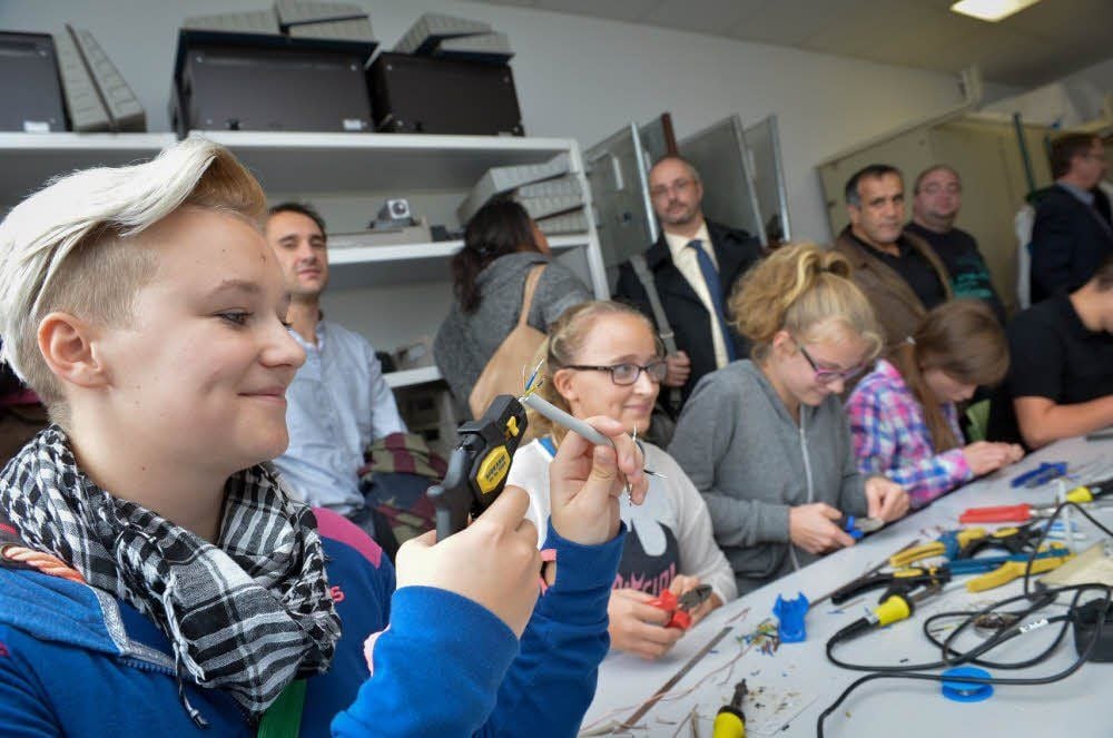 Sarah Göttl (links) führte die Gäste herum und zeigte auch selbst, woran die Schüler arbeiten - zum Beispiel beim Entfernen der Isolierung von Kabeln.
