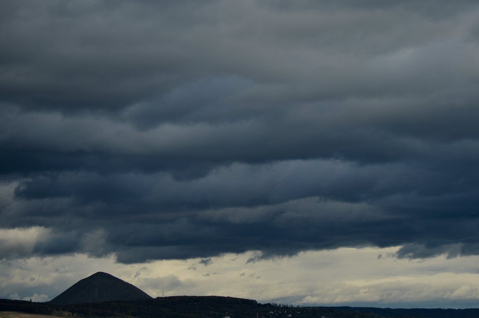 Eine dunkle Wolkenfront zieht in Sangerhausen über eine Abraumhalde.