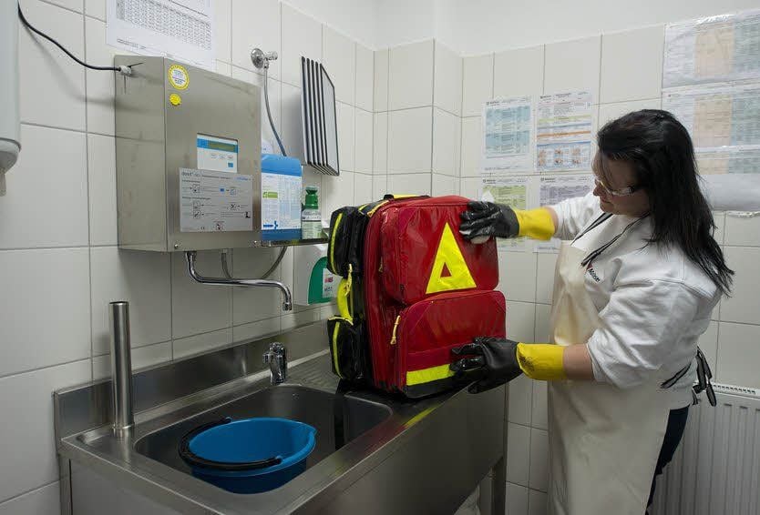 Rettungsassistentin Nadine Grünhagen desinfiziert nach einem Einsatz den Rettungsrucksack. Die passende Lösung dafür kommt aus dem Dosierautomaten an der Wand.