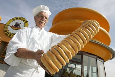 Der Baumkuchen-Bäcker Rolf Friedrich präsentiert vor seiner neuen Bäckerei in Wernigerode (Harz) einen Baumkuchen. (Foto: dpa)