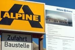 Firmenschilder des österreichischen Bauunternehmens Alpine hängen am Zaun des Münchner Fußball-Stadion "Allianz-Arena". (Foto: dpa)