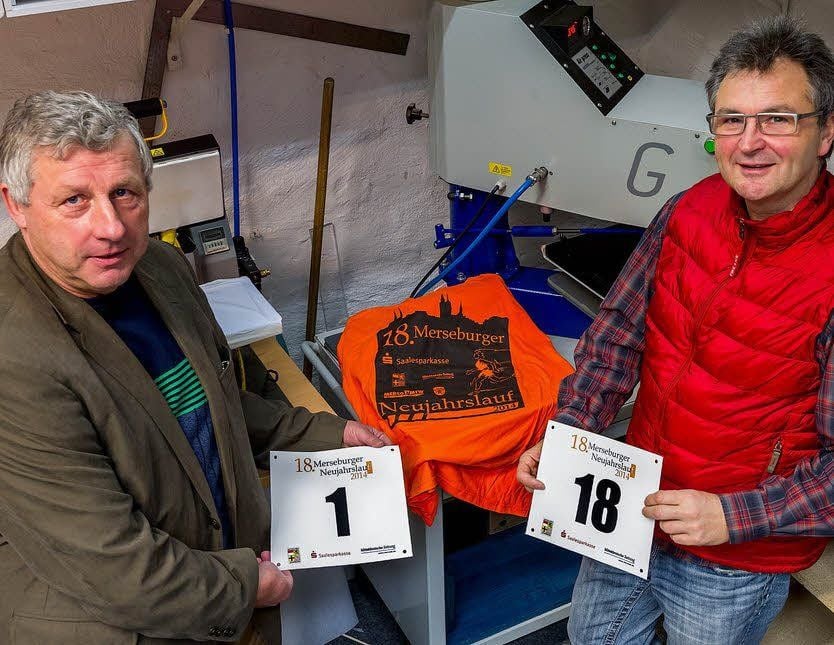 Jürgen Schauseil (li.), der KSB-Geschäftsführer, und Horst Naumann von der Firma Merco präsentieren die Startnummern und das 2014er Lauftrikot des Merseburger Neujahrslaufes.