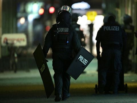 Ein Polizist läuft mit Schutzschildern in Berlin während eines Polizeieinsatzes zu einer Bank. Ein Bankräuber hatte bei einem Überfall in Berlin einen Angestellten als Geisel genommen. (FOTO: DPA)