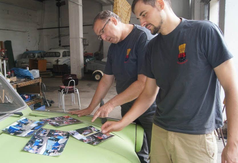 Frank Huke (li.) und Lutz Lorenz sondieren einige der auf einer Trabbi-Haube ausgebreiteten Vorlagen für den Vereins-Wandkalender.