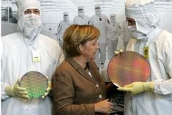 Bundeskanzlerin Merkel (CDU) lässt sich am Dienstag (24. Oktober) anlässlich des zehnten Geburtstags der AMD-Niederlassung in Dresden von zwei Mitarbeitern des US-Elektronikkonzerns Chipwafer zeigen. (Foto: dpa)
