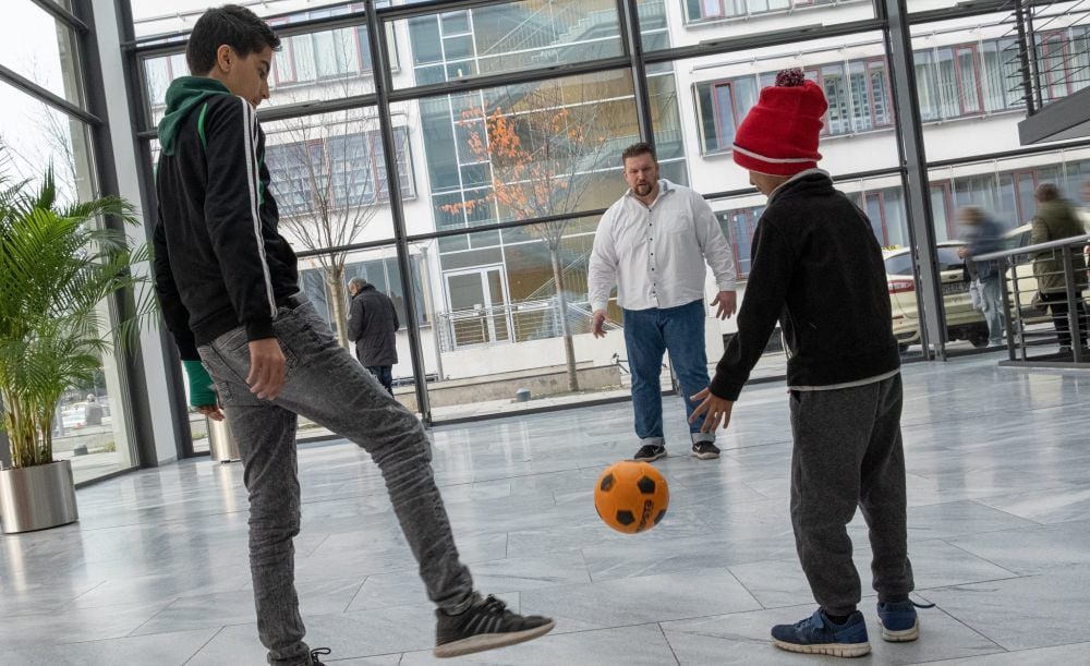 Sporttherapeut Torge Wittke (Mitte) spielt im Foyer der Klinik mit jungen Patienten Fußball.
