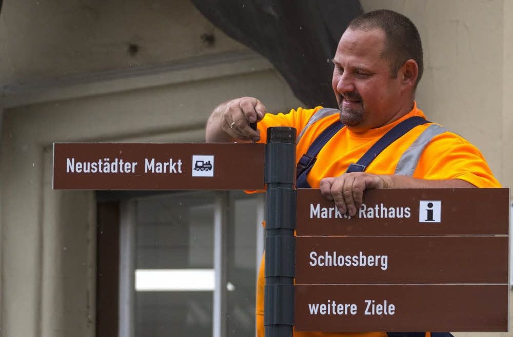 Karsten Böttcher montiert die letzten Schilder für das neue touristische Leitsystem für Fußgänger.