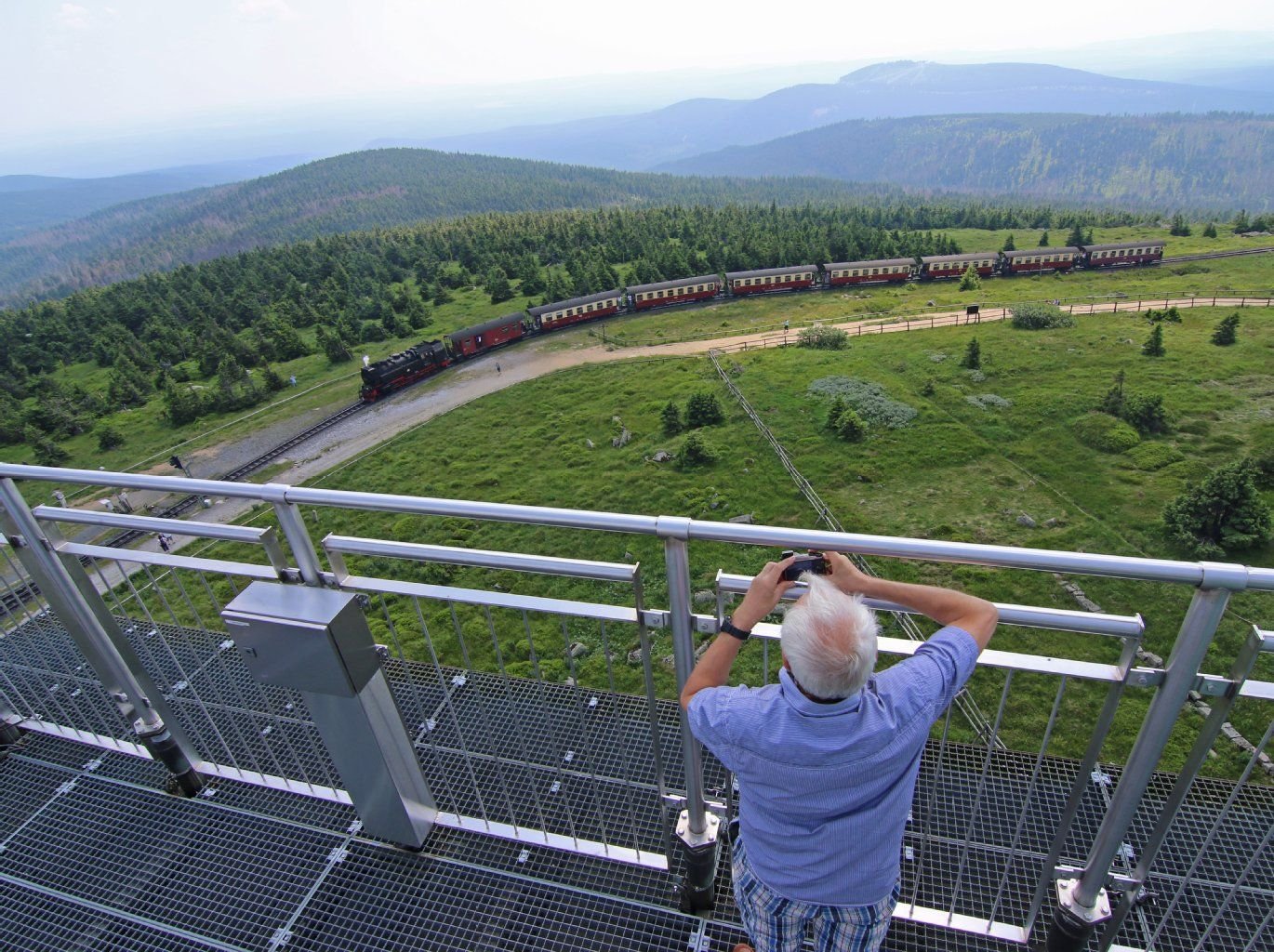 Ein Brockenbesucher beobachtet auf dem Brocken (Sachsen-Anhalt) einen Zug der Harzer Schmalspurbahn HSB.