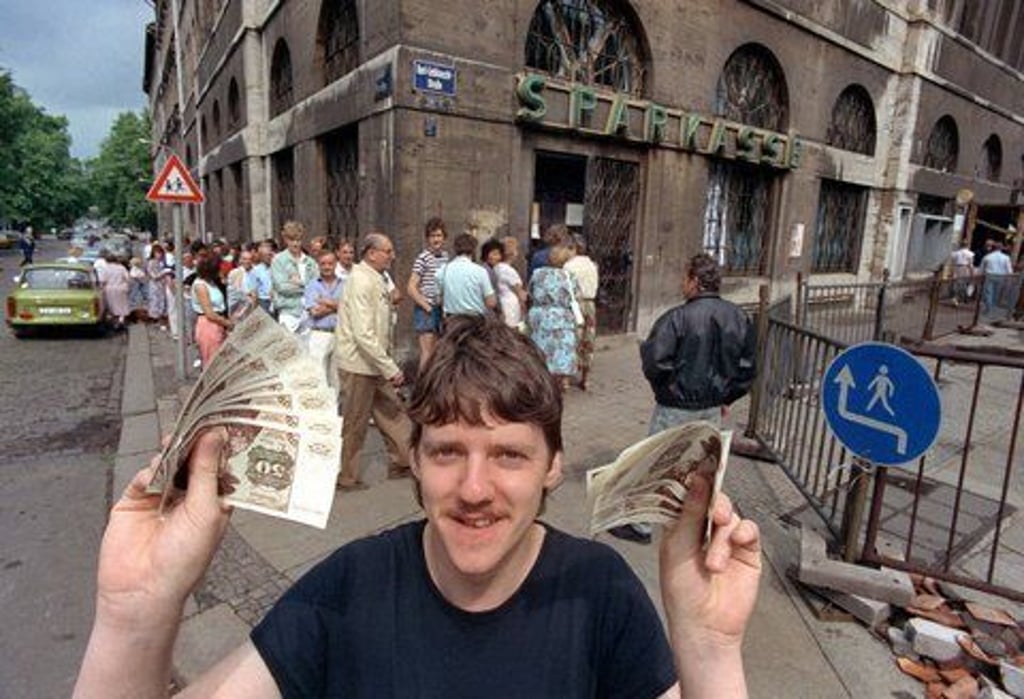 Nach langem Schlangestehen vor einer Leipziger Bank freut sich dieser junge Mann über seine D-Mark-Banknoten, aufgenommen am 1.7.1990, der Tag der innerdeutschen Währungsunion.