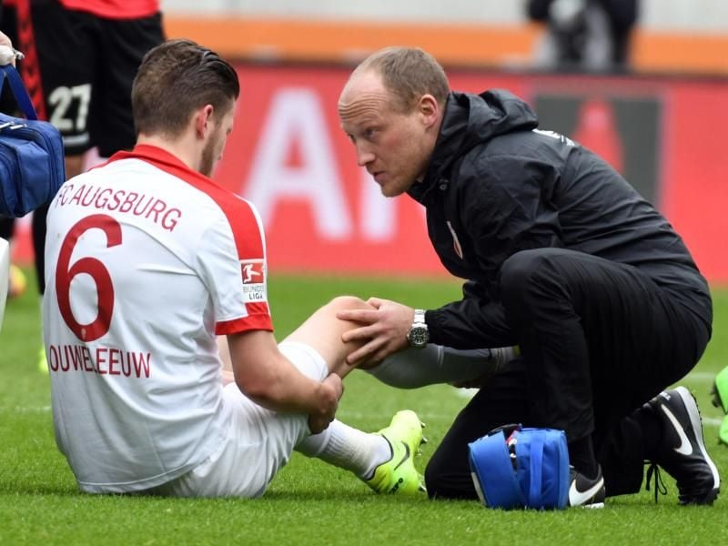 Augsburgs Jeffrey Gouweleeuw (l) wird von Arzt Peter Stiller am Knie behandelt. Foto: Stefan Puchner