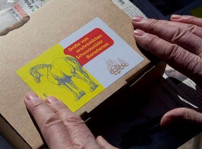 Georg Beckmann klebt in Stegen bei Freiburg einen Aufkleber auf ein Päckchen mit Pferdemist. Den Mist der Stute Iphrane verschickt Beckmann als Päckchen im Kundenauftrag als Rachegeschenk. (FOTO: DDP)