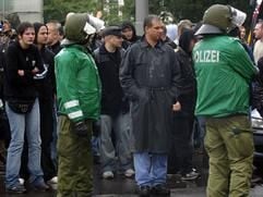 Der Hamburger Rechtsextreme Christian Worch (M.) steht am Samstag (1. Oktober 2005) in Leipzig zwischen zwei Polizisten im Regen. Worch hatte einen Aufmarsch von Neonazis durch die Stadt veranstalten wollen. (Foto: dpa)