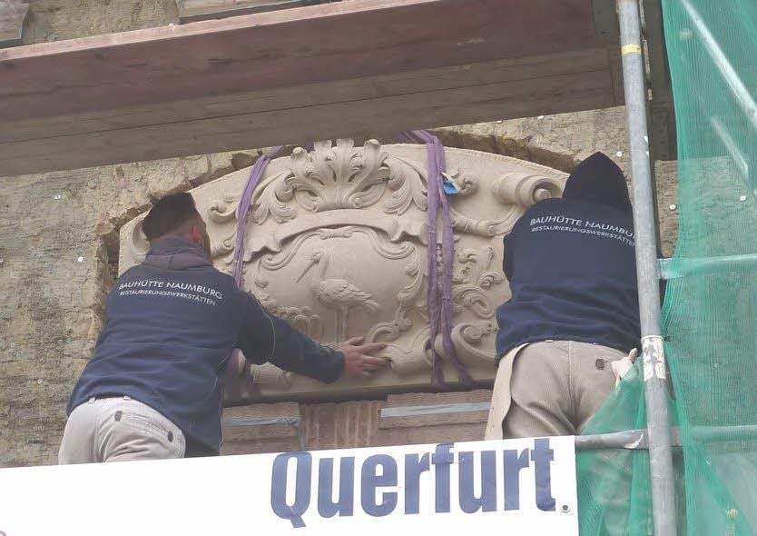 Mitarbeiter der Bauhütte Naumburg haben ein 800 Kilo schweres Hauswappen aus Sandstein an das Storchenhaus angebracht.