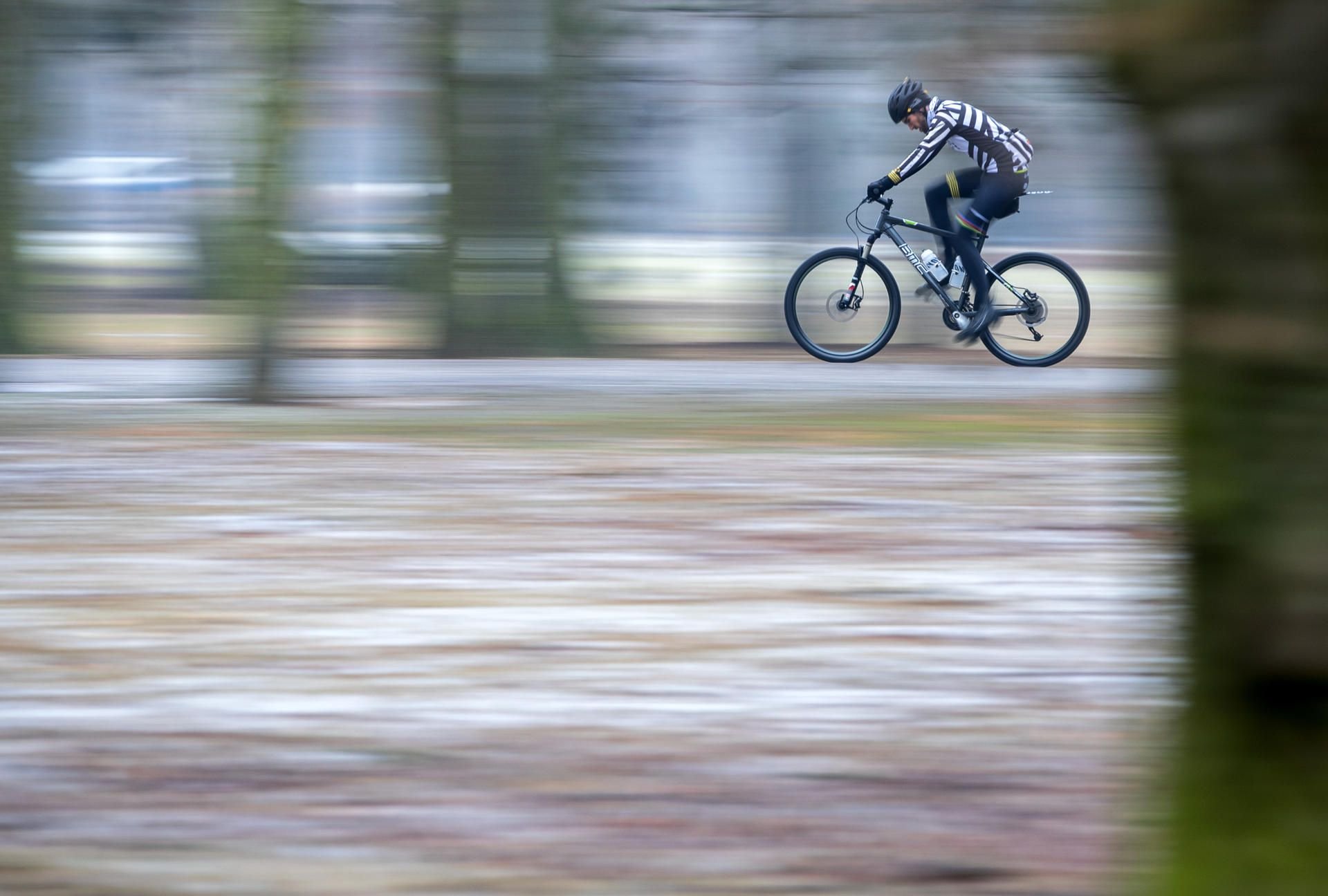 Ein Fahrradfahrer fährt durch einen teilweise verschneiten Park. Grau und feucht zeigt sich das Wetter am Wochenende.
