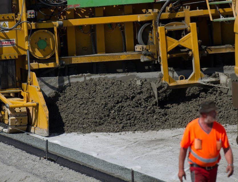 Mit einer Straßenbaumaschine wird Beton aufgetragen.