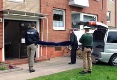 Bestatter tragen unter den Augen von Polizeibeamten am Mittwoch (13.04.2005) im Lübecker Stadtteil St. Lorenz den Leichnam eines 18-Jährigen aus dem Haus, in dem ein Polizist zuvor den jungen Mann bei einem Einsatz erschossen hatte. (Foto: dpa)