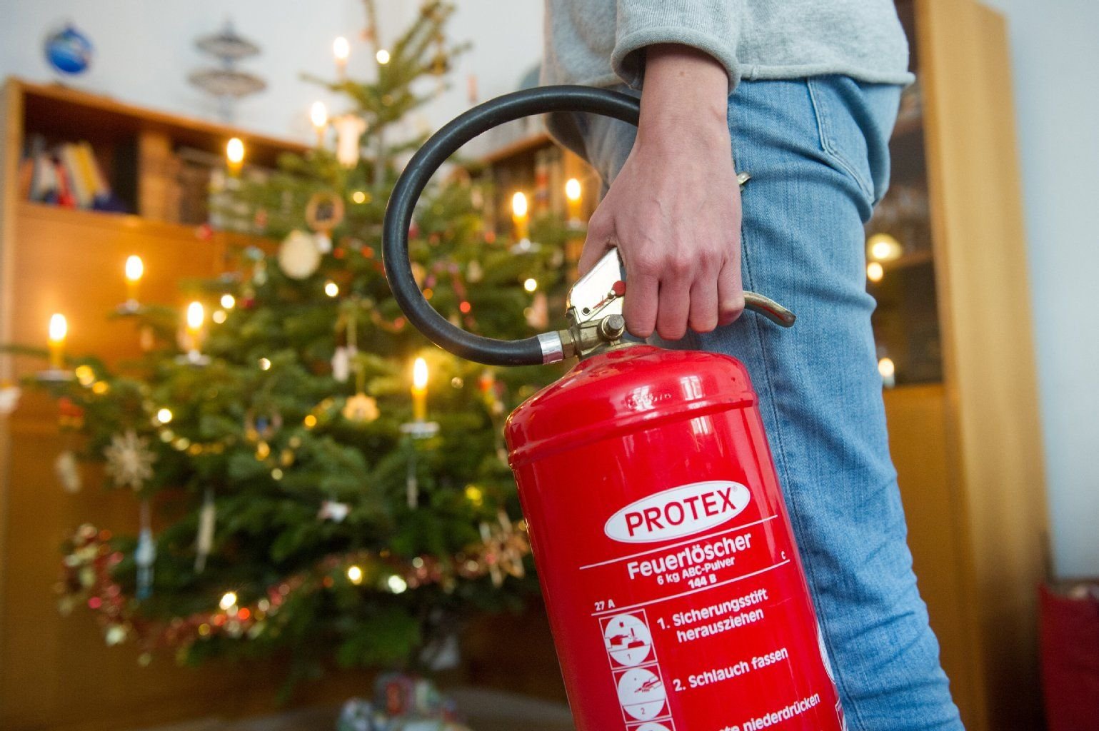 Feuerlöscher immer griffbereit haben – wer echte Kerzen an seinem Weihnachtsbaum verwendet, muss wachsam sein.
